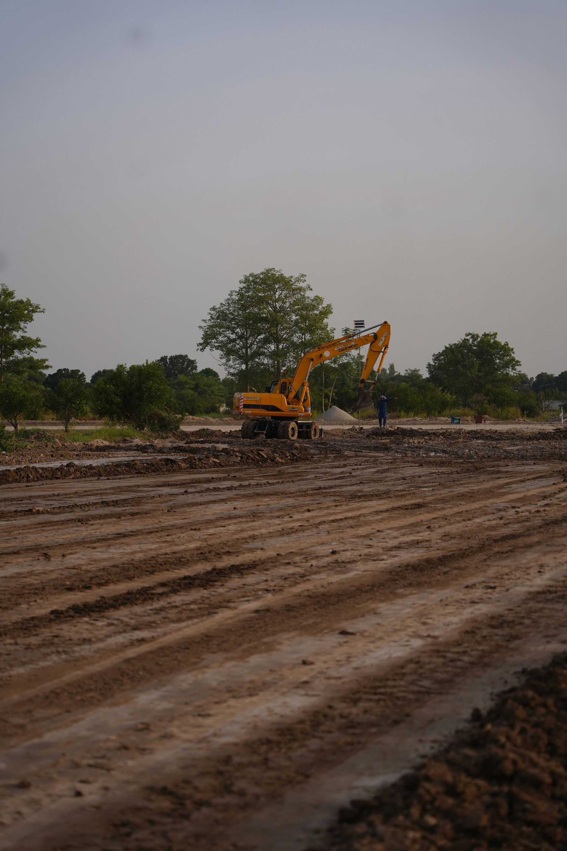 An excavator works on a construction site with a person